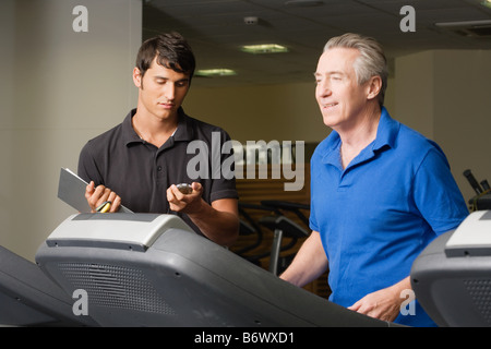 A personal trainer helping a man on a treadmill Stock Photo