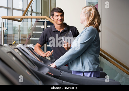 A personal trainer and woman on a treadmill Stock Photo