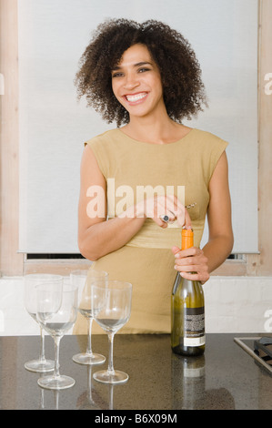 A young woman opening a bottle of wine Stock Photo