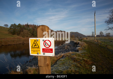 telegraph power wires over the river lune in the valley near Lancaster with a sign warning of the lines and the danger of death Stock Photo