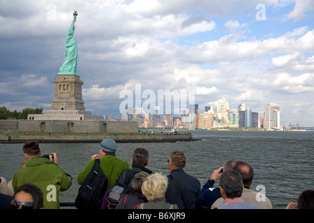 Tourists view the Statue of Liberty and Lower Manhattan from New York Harbor New York USA Stock Photo
