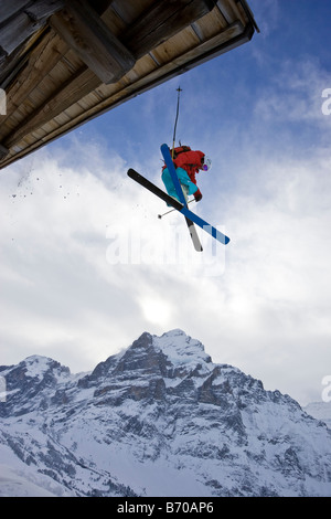 A young man skis off the roof of an alpine hut in Grindalwald, Switzerland. Stock Photo