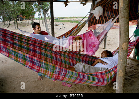 Suriname, Matapica National Park. Tourists relaxing in hammock on the beach. Stock Photo