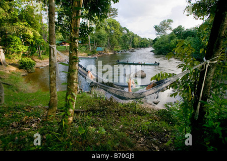 Suriname, Laduani, Nieuw Aurora, at the bank of the Boven Suriname river. Anaula Nature Resort. Woman relaxing in hammock. Stock Photo