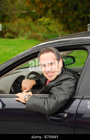 Smiling man looking out of a car window Stock Photo