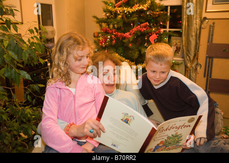 An auntie reads a christmas story to her neice and nephew at christmas time Stock Photo