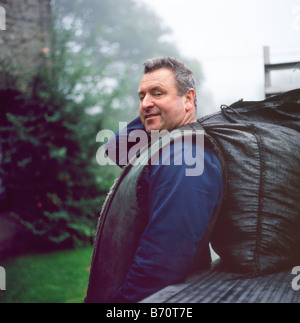 Portrait of coal man Robert Brown of Sennybridge delivering coal sack for solid fuel stove in Llanwrda Carmarthenshire Wales UK BritainKATHY DEWITT Stock Photo