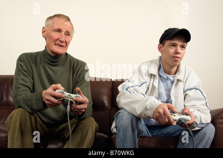 A teenager playing on a games console (xbox 360) with a elder man Stock Photo