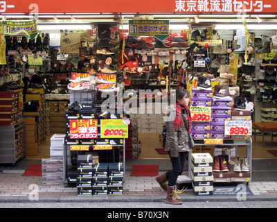 January, 2009. A girl walks past a discount shoe store in the Ueno district of Tokyo, Japan. Stock Photo