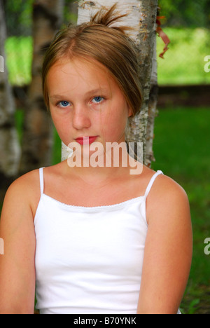 Portrait of a young pretty girl sitting under a birch tree in a park Stock Photo
