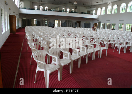 Large number of white color chairs on red carpet arranged for important public function or meeting in a huge hall with balcony Stock Photo