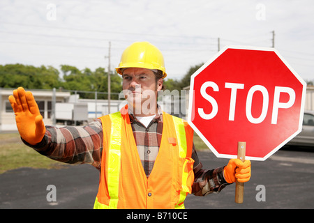 A construction worker holding a stop sign and directing traffic Stock Photo