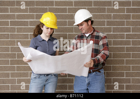 A construction foreman going over blueprints with a female apprentice Stock Photo
