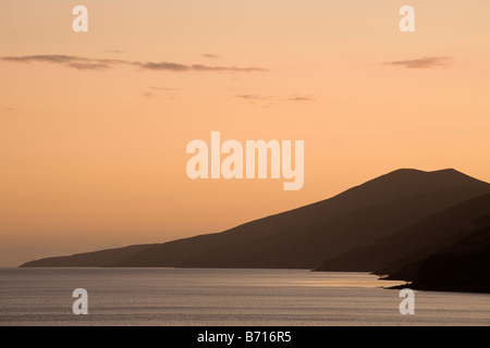 Dingle Peninsula from Inch Strand. The sunset casts a soft glow over the mountains and shoreline of the Dingle Stock Photo