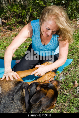 Woman giving a tummy rub to her shepherd doberman mix dog Stock Photo