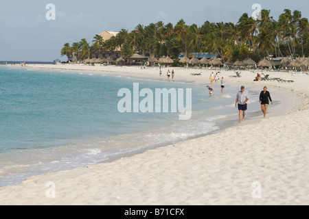 People walking along Eagle Beach on the Caribbean island of Aruba Stock Photo