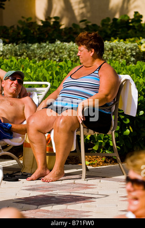 Palm Beach Shores , mature middle aged large portly lady seated in swimming costume by sun lounger sunbathing by pool travel USA Stock Photo