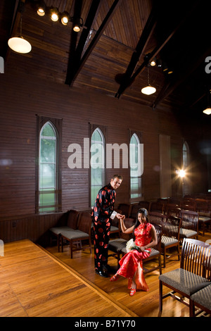 Young couple wearing traditional Asian clothing and holding hands in church Stock Photo