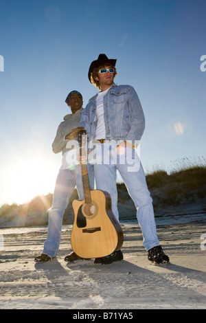 Young interracial couple standing with guitar on beach Stock Photo