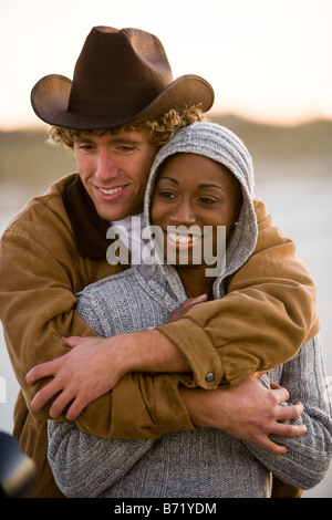 Young interracial couple standing on beach with arm around Stock Photo