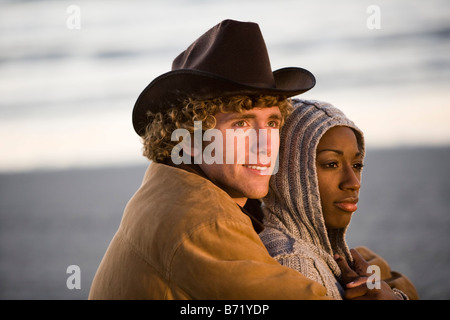 Young interracial couple sitting on beach Stock Photo