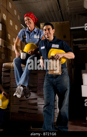 Two co-workers taking a coffee break  in storage warehouse Stock Photo