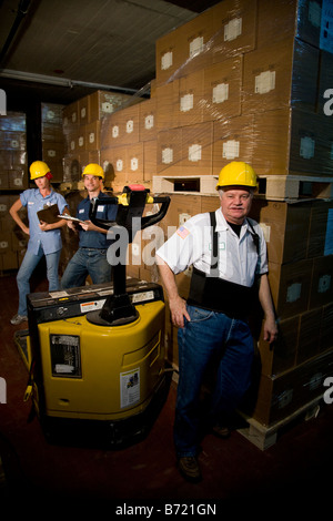 Three workers in hard hats in storage warehouse Stock Photo