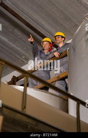 Blue-collar workers in factory overlooking storage tanks Stock Photo