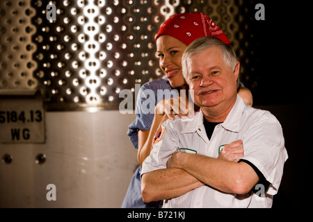 Workers in factory next to storage tanks Stock Photo
