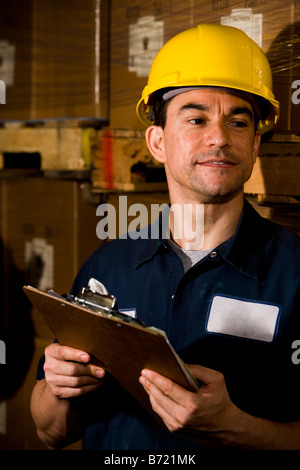 Male worker wearing hard hat standing in storage warehouse Stock Photo
