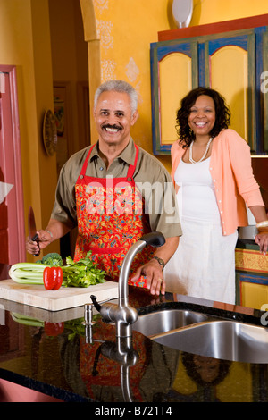 Middle-aged African-American couple preparing to cut vegetables in kitchen Stock Photo