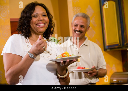 Happy middle-aged African American couple eating in kitchen at home Stock Photo