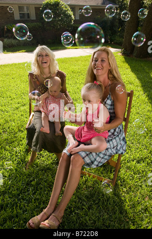 Mothers with baby and girl with Downs Syndrome, sitting in backyard Stock Photo