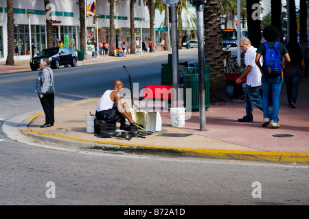 Miami street scene , busker plays music on home made drums , percussion , on street corner , ignored by passers by Stock Photo