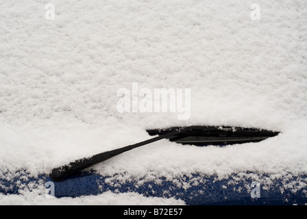 Snow covered car window with wipers, macro, close up. Car wiper blades  clean snow from car windows. Flakes of snow covered the car. Industrial  Stock Photos