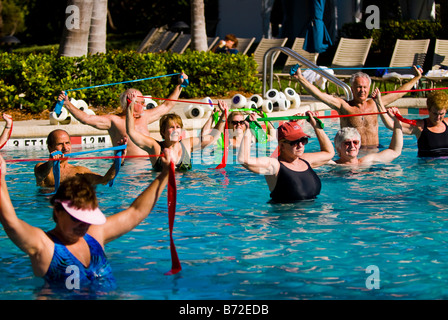 Palm Beach Shores , mature smiling middle aged large men & women in swimming pool do aqua aerobics with elastic stretch strips Stock Photo