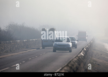 cars and vans driving along a foggy coastal road in the morning in county down Northern Ireland UK Stock Photo