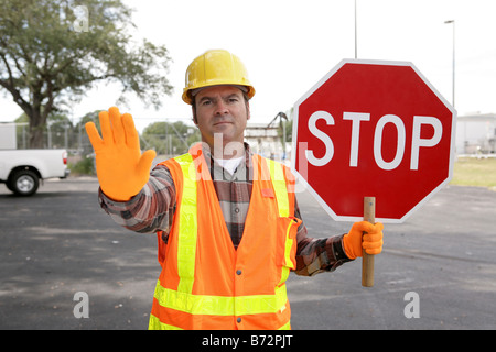 A construction worker holding a STOP sign and directing traffic Stock Photo