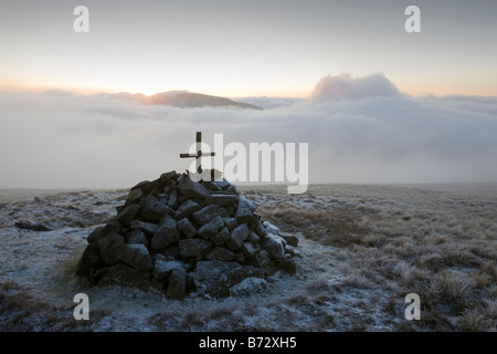 A cross on a cairn near the summit of Caudale Moor at sunset in the Lake District UK Stock Photo