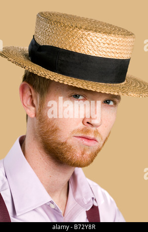 Young man with Red Hair and beard wearing straw hat and suspenders Stock Photo