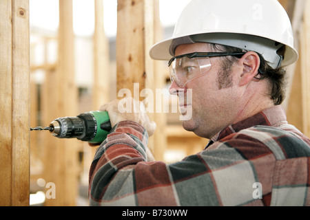 A construction worker drilling and wearing proper safety equipment according to OSHA regulations Authentic and accurate content Stock Photo