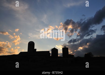 Silhouettes of barns and silos on a New York dairy farm at sunset Stock Photo