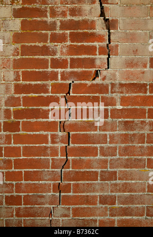 large tall red brick wall with crack going full length from the top to the bottom Stock Photo