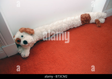 A dog shaped draft excluder lies at the base of a door. Stock Photo