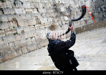 A religious Jew blowing a shofar at the Western Wall in in the Old City of Jerusalem during a snow storm. Stock Photo