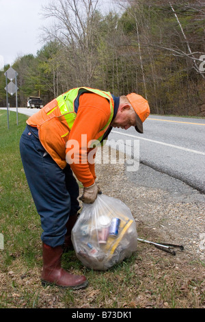 County utility worker picks up litter alongside highway Stock Photo