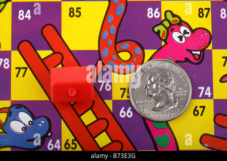 one us quarter dollar 25c coin and toy red house on a snakes and ladders board with house on the ladder and quarter on the snake Stock Photo