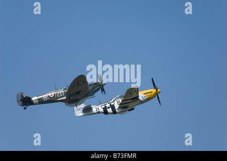 British Spitfire and American P51 Mustang fighter aircraft flying side-by-side in a clear blue sky. Stock Photo