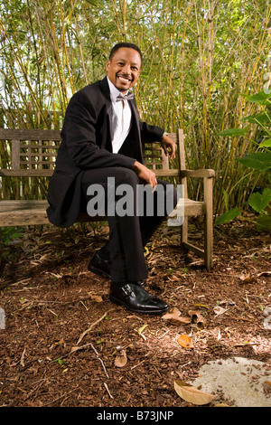 Portrait Of A Groom Sitting Alone On A Wooden Bench Next To Bouquet Of 