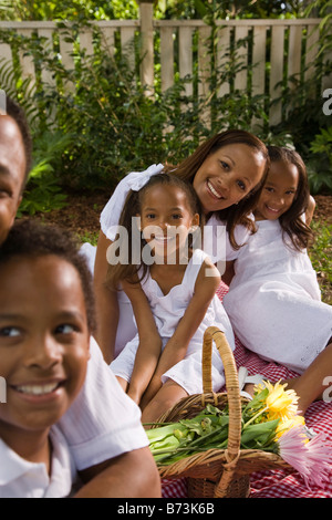 Happy African-American family posing on picnic blanket in yard Stock Photo